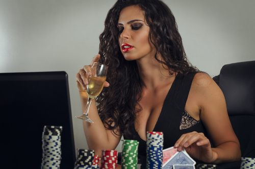 jeune femme sensuelle buvant du champagne et jouant au poker en ligne