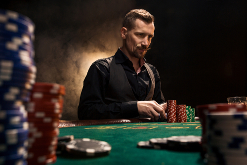 jeune homme assis à une table de poker avec des cartes et des jetons