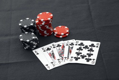 quinte flush royale trefle posée sur une table noir avec des jetons de casino