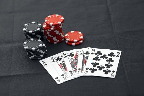 quinte flush royale trefle posée sur une table noir avec des jetons de casino