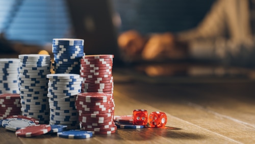 plusieurs piles de jetons de casino posés sur une table avec des dés rouge à côté